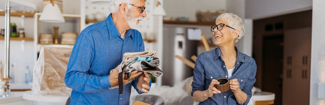 Senior couple packs for a move while smiling at each other. 